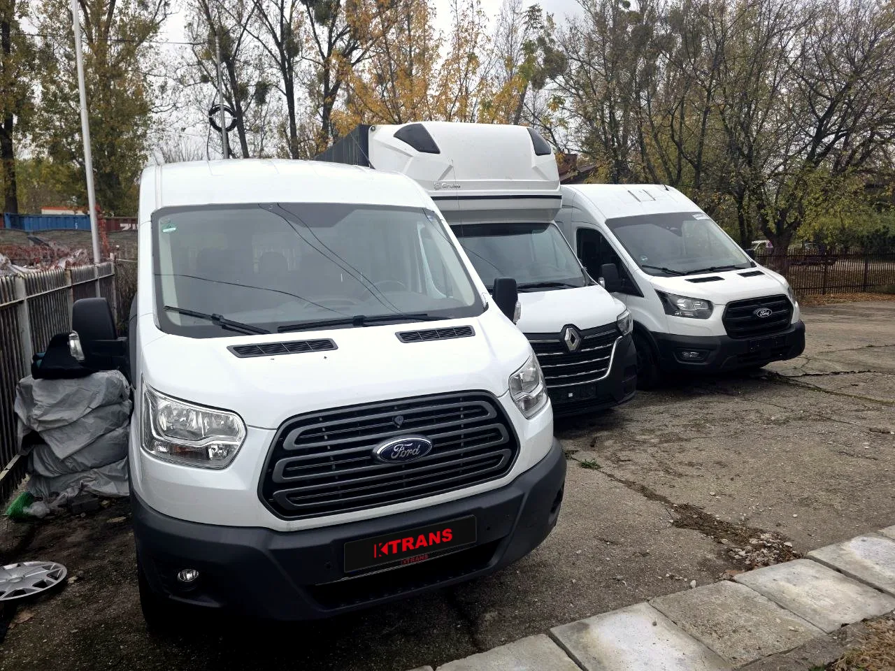 Три буси KTRANS на майданчику у Варшаві: попереду Ford Transit з табличкою KTRANS, за ним Renault Master з тентом і новий Ford Transit
